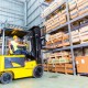 Asian fork lift truck driver lifting pallet in storage